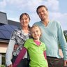 Eine kleine Familie, im Hintergrund ist ein Haus mit einer Photovoltaikanlage