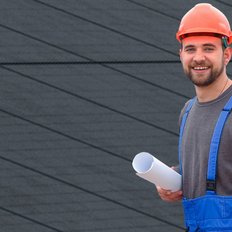 Ein Installatör mit einer Photovoltaikanlage im Hintergrund